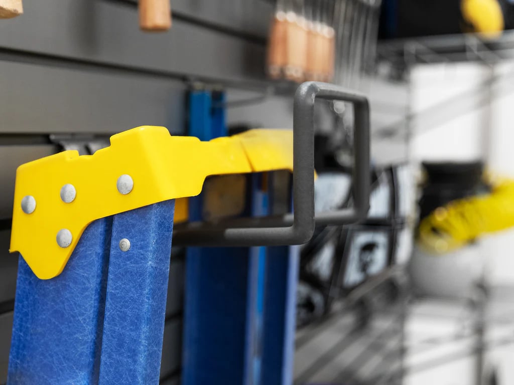 close up of a ladder hanging on a hook on gray slatwall 