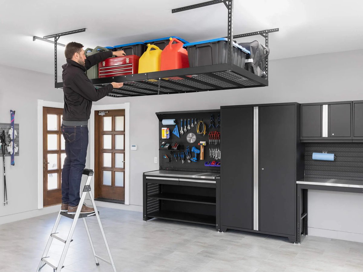 man removing items from large black overhead storage system in garage
