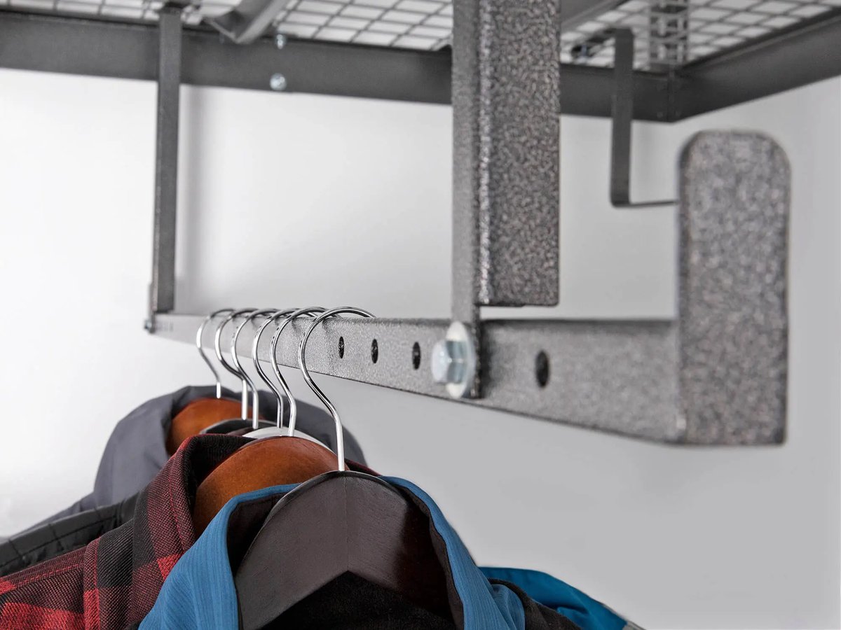 clothes hanging from bar under ceiling mounted storage rack