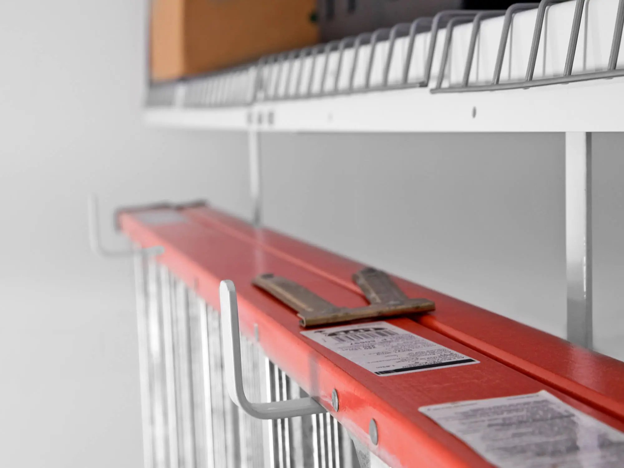 ladder hanging from bottom of overhead storage rack