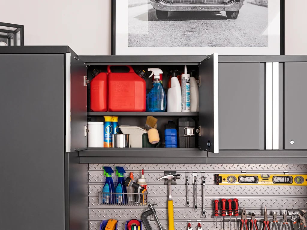 Upper cabinets open in garage with cleaning supplies and slatwall tools