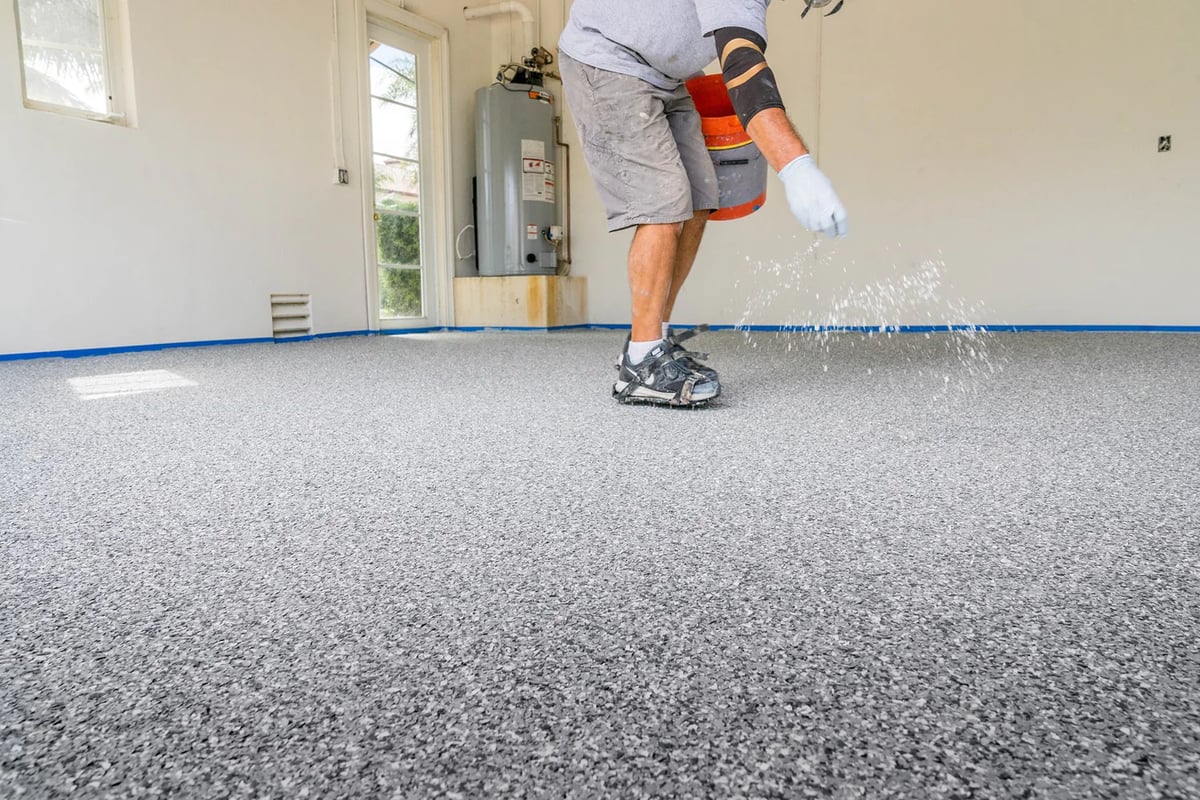man sprinkling flake on polyaspartic floor coating
